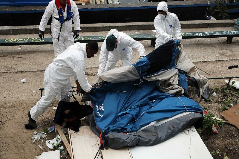 Government workers remove a tent Monday to clear out a makeshift migrant camp along side of the Canal Saint Martin in central Paris, France.  