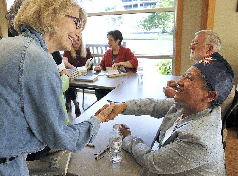 LaVerne Bell-Tolliver (right) shakes hands with Audrey Evans at a book signing during the Arkansas Literary Festival at the Central Arkansas Library System’s Darragh Center.  