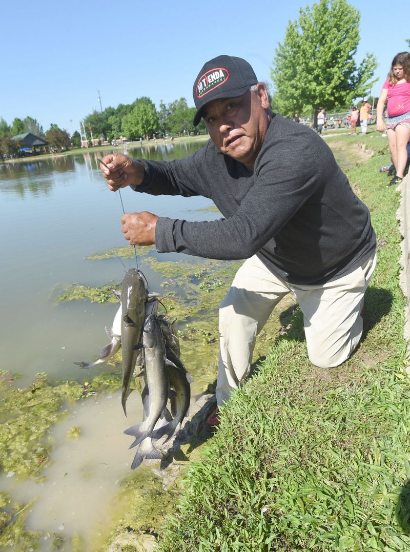 NWA Democrat-Gazette/FLIP PUTTHOFF Felix Soto shows a stringer of channel catfish he caught during the Care Community Center family fishing derby at Veteran's Park in Rogers late last month. Worms or nightcrawlers are good live bait for channel catfish. Flathead catfish prefer sunfish or large minnows.