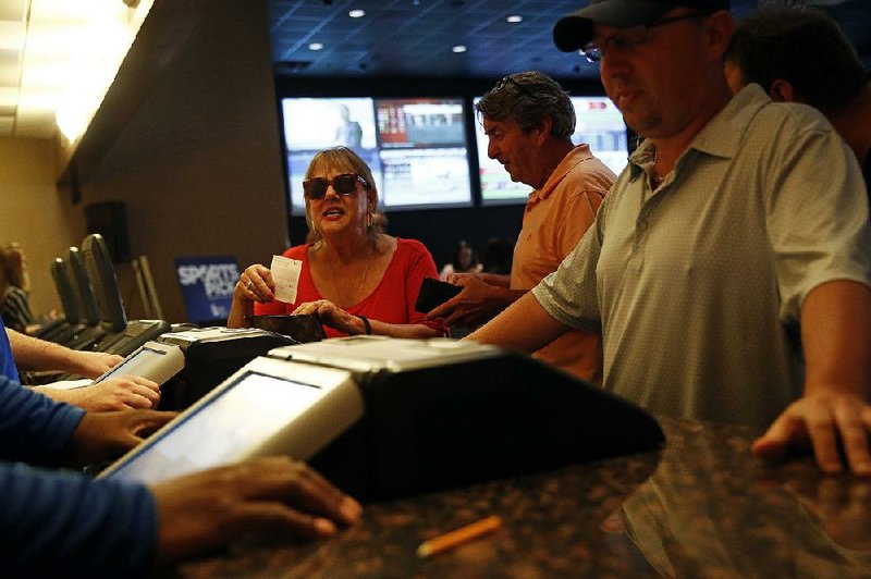 Gambler Marcia Poppas Devaney (left) tucks a receipt for a sports bet into her purse Tuesday at the Race and Sports Book at Dover Downs Hotel and Casino in Dover, Del. The market for legal sports gambling in the United States widened significantly Tuesday with the expansion of single-game sports bets in Delaware, less than a month after the U.S. Supreme Court cleared the way for states to accept the bets.