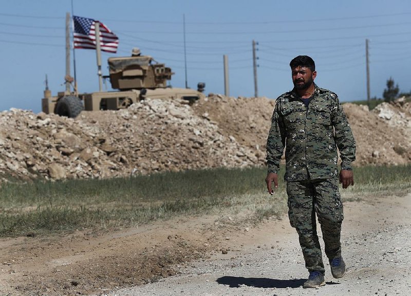 A U.S.-backed Syrian Majbji Military Council solider passes a U.S. military position in Manbij, northern Syria, in this April file photo. The Kurdish militia units are pulling out of the town to prevent a rift between the U.S. and Turkey.