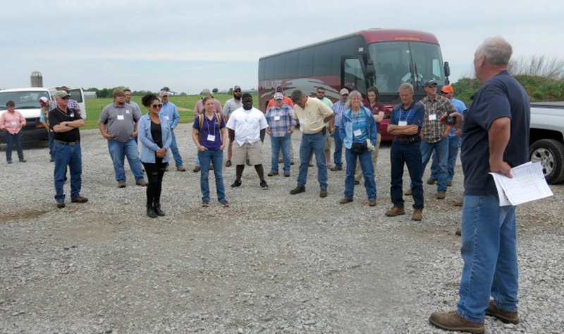 Westside Eagle Observer/SUSAN HOLLAND Gravette dairy farmer Bill Haak (right) welcomes visitors to his farm. A group of about 40 forage specialists from the southeastern United States toured his farm May 15 while in the area attending a conference at the University of Arkansas. Haak answered questions about his operation, which has recently been designated an Arkansas Discovery Farm. Water quality research is done on Discovery Farms.