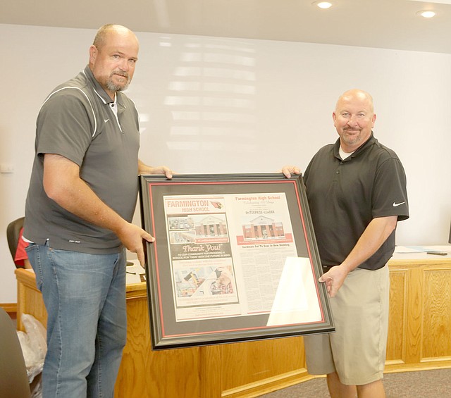 LYNN KUTTER ENTERPRISE-LEADER Farmington School Board President Jeff Oxford, left, presents high school Principal Jon Purifoy with framed pages from a special newspaper section produced by the Enterprise-Leader to celebrate the first 100 days of the new high school building.