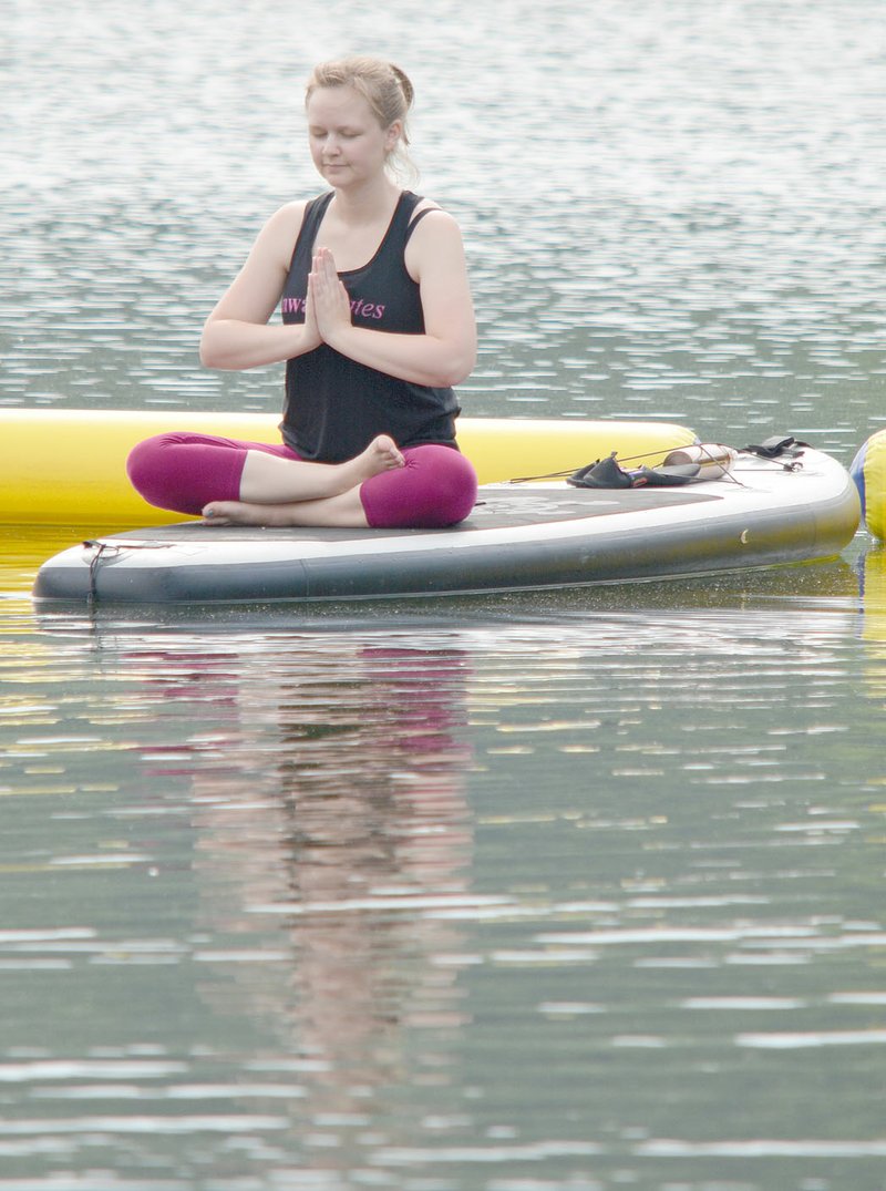 Keith Bryant/The Weekly Vista Holly Parlier, who owns property in Bella Vista, sits on a paddleboard during a guided meditation session at the Lake Avalon Beach.