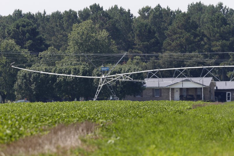 In this July 21, 2017, file photo an irrigation system is seen in front of a home across the road from a farm that has hogs owned by Smithfield Foods in Farmville, N.C.  