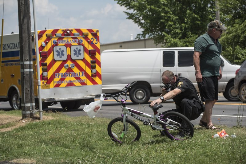 Springdale police officer Carey Landrum takes photos of a bicycle that was involved in a car accident Wednesday, June 6, 2018, on Old Missouri Road near the intersection of East Huntsville Avenue in Springdale.