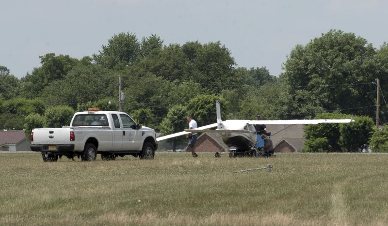 A plane with a damaged wing is looked at Wednesday, June 6, 2018, before being hauled off the runway at the Springdale airport.  