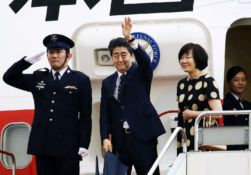 Japanese Prime Minister Shinzo Abe (center) and his wife, Akie, board a plane Wednesday in Tokyo for a trip to Washington and then to the G-7 summit in Quebec. 