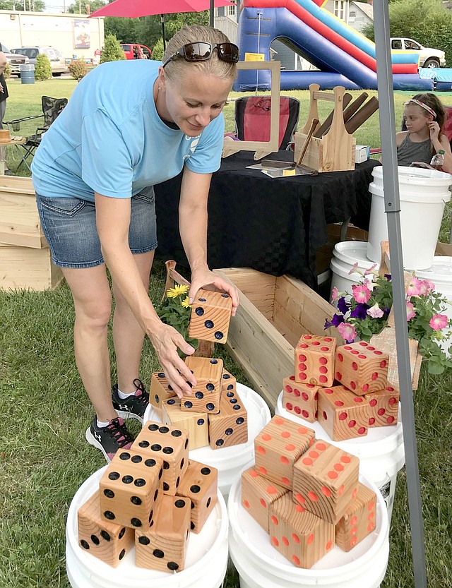 Sally Carroll/McDonald County Press Candace Watson of Goodman arranges some large wooden dice at her family's booth at Noel's First Friday event. She and her husband, Pat, operate OutBack Creations, selling all types of wood items and gifts.
