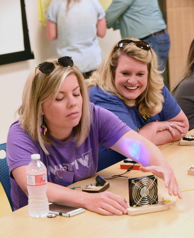  Lindsey Evans (left) and Alexandra Wakelyn work on an experiment at the Amazeum to complete an electric circuit that turns on a small fan.