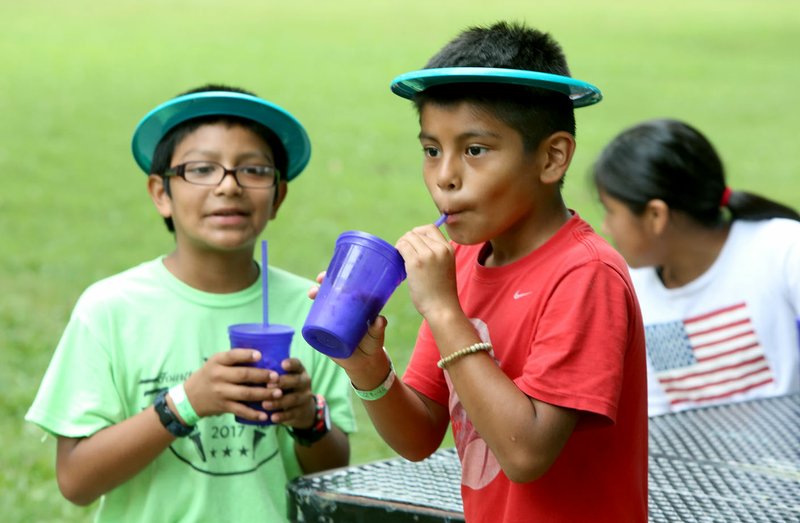  Irvin Martinez (left), 10, and Alfredo Hernandez, 9, enjoy a frozen ice drink July 14, 2017, at the annual CDBG in the Park picnic at Walker Park Pavilion in Fayetteville.