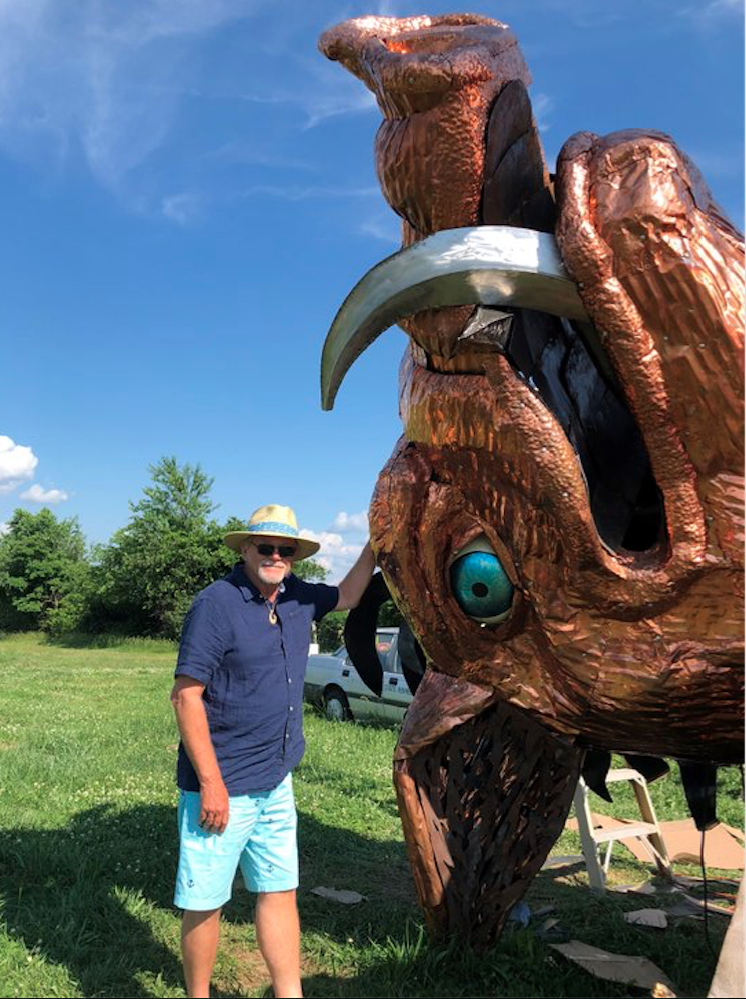 Hogeye Inc. owner Cliff Slinkard stands next to the head of a 25-foot hog statue that will be installed Sunday outside the business, located on Highway 62 between Fayetteville and Farmington. 