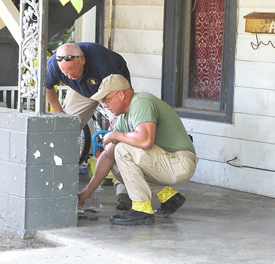 The Sentinel-Record/Richard Rasmussen SUSPICIOUS DEVICES: Arkansas State Police Bomb Squad members Sgt. Mike Dawson, left, and Cpl. Hunter Glover look over some suspicious devices located at 405 Alcorn St. after a resident reportedly died of a fatal drug overdose there early Thursday.