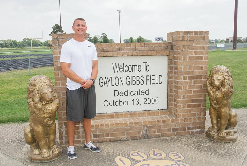 Andrew Roberson, the new football coach at England High School, stands next to the Gaylon Gibbs Field sign inside the stadium on the school campus. Roberson was hired earlier this year to replace Matt Garrett. Roberson was formerly an assistant coach at Conway Christian High School.