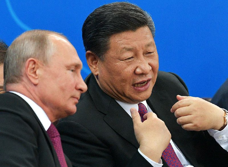 Russian President Vladimir Putin and Chinese President Xi Jinping talk Friday while watching a Chinese and Russian youth ice hockey match Friday in Tianjin, China.  
