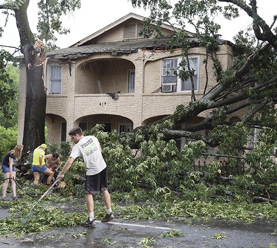 The Sentinel-Record/Grace Brown CLEANING UP: Residents of a small apartment building at 619 Hobson Ave. work to clear the roadway after a tree fell and grazed the roof of the apartment following a storm that left the area heavily damaged on Friday.