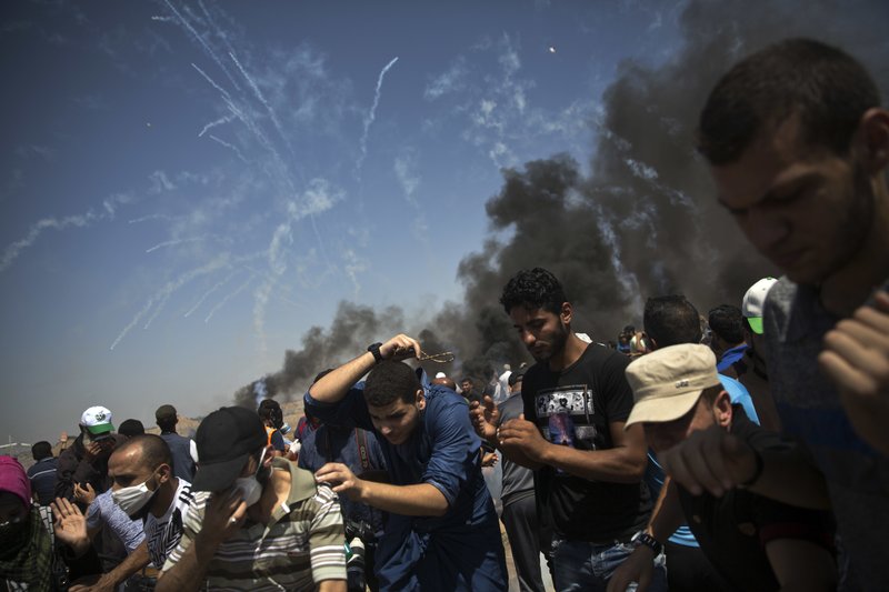 Tens of teargas canisters fired by Israeli troops, fall over Palestinian protesters at the Gaza Strip's border with Israel, Friday, June 8, 2018. Thousands of Palestinians are streaming toward the fence separating Gaza from Israel for a protest against the decade-long blockade of their territory. (AP Photo/Khalil Hamra)