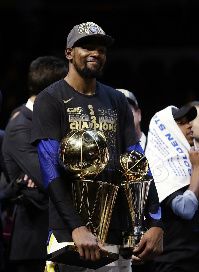 Kevin Durant of the Golden State Warriors holds the NBA championship and MVP trophies after the Warriors defeated the Cleveland Cavaliers 108-85 in Game 4 of the NBA Finals on Friday night in Cleveland. Durant was named Finals MVP for the second consecutive year. 