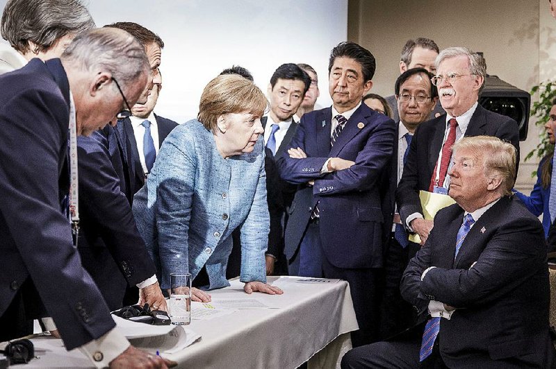 German Chancellor Angela Merkel speaks to President Donald Trump as Japanese Prime Minister Shinzo Abe, U.S. national security adviser John Bolton (top right) and others watch Saturday during the G-7 summit in La Malbaie, Quebec.   
