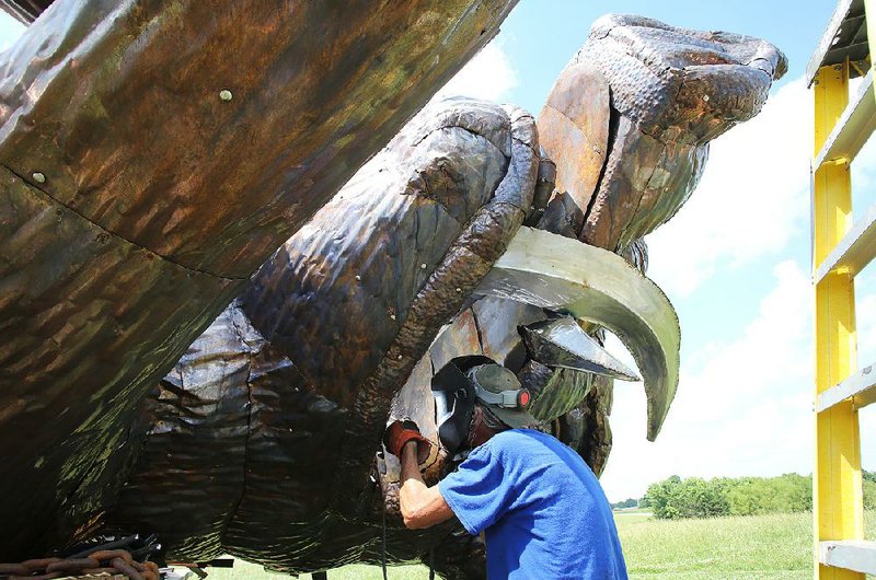 Eugene Sargent works last week on the head of a 25-foot-tall boar statue at his studio in rural Washington County. The statue was commissioned by Cliff Slinkard with Hogeye Inc. to stand outside the company office at at the Calypso Crossing Office Park in Fayetteville. 