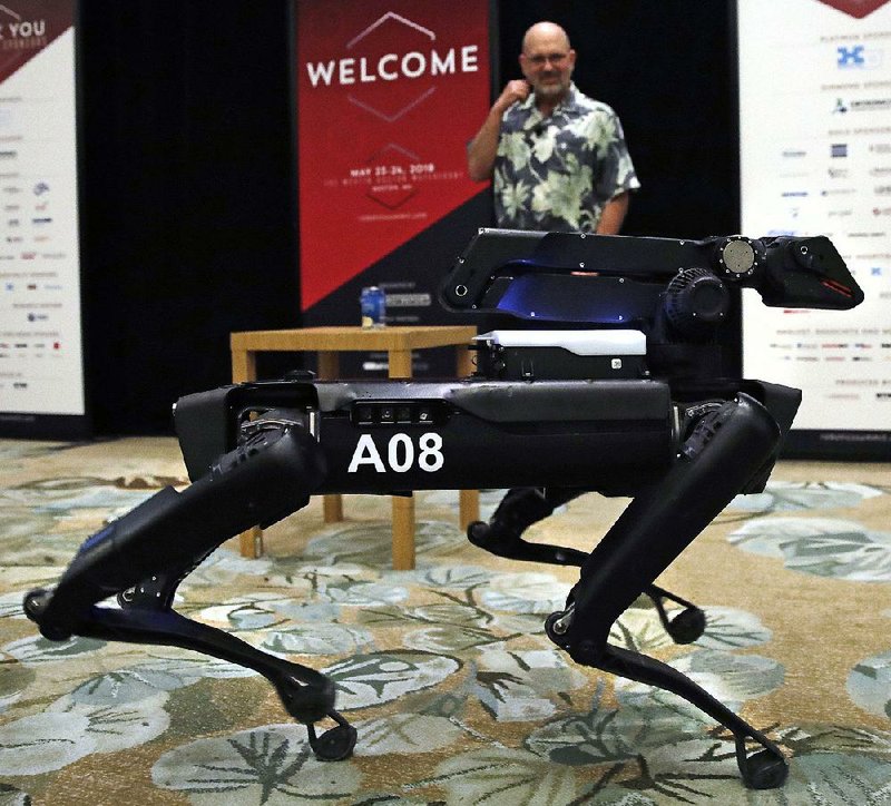 A Boston Dynamics SpotMini robot walks through a conference room during a robotics summit in Boston in May.  