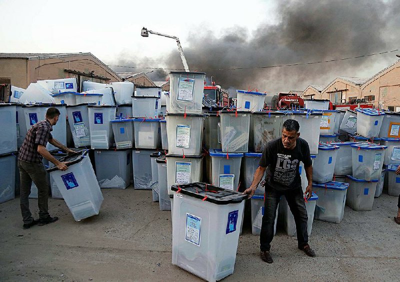 Iraqis work to salvage ballot boxes Sunday as smoke rises from a fire that engulfed a Baghdad depot where the ballots were being stored for a recount. The fire raised more concerns about the legitimacy of national elections that were already marred by fraud accusations.  