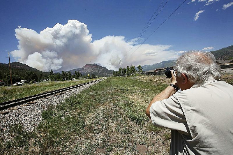 Paul Boyer of Durango, Colo., takes a photo of a plume as it rises from a wildfire near Hermosa, Colo. on Saturday.  