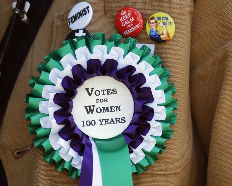 A participant wears a rosette as she takes part in a march through the streets to celebrate 100 years since women were granted the vote, in London, Sunday June 10, 2018. (AP Photo/Frank Augstein)