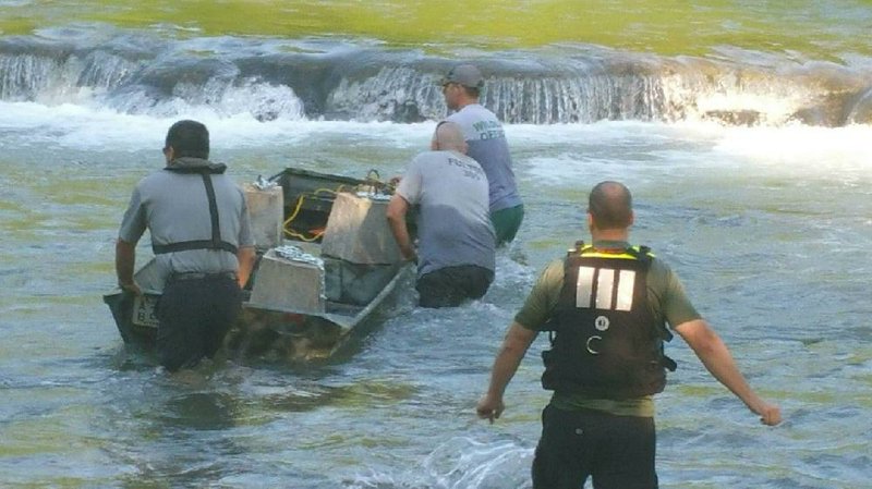 Wildlife officers from the Arkansas Game and Fish Commission work to barricade the area where a sinkhole opened in the Spring River on Saturday afternoon, killing a kayaker who was sucked into a resulting whirlpool.