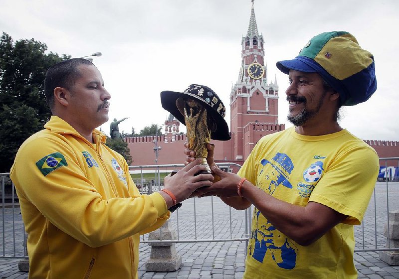 Brazilian fans hold a replica of the World Cup trophy Monday near the Kremlin in Moscow. The 21st World Cup begins Thursday when host Russia takes on Saudi Arabia. 