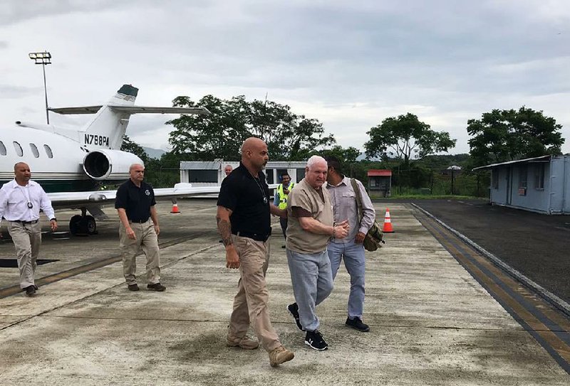 Former Panamanian President Ricardo Martinelli is escorted by a U.S. marshal after arriving at Tocumen International Airport in Panama City on Monday. Martinelli returned to Panama to face political espionage and embezzlement charges after being extradited from the United States. 