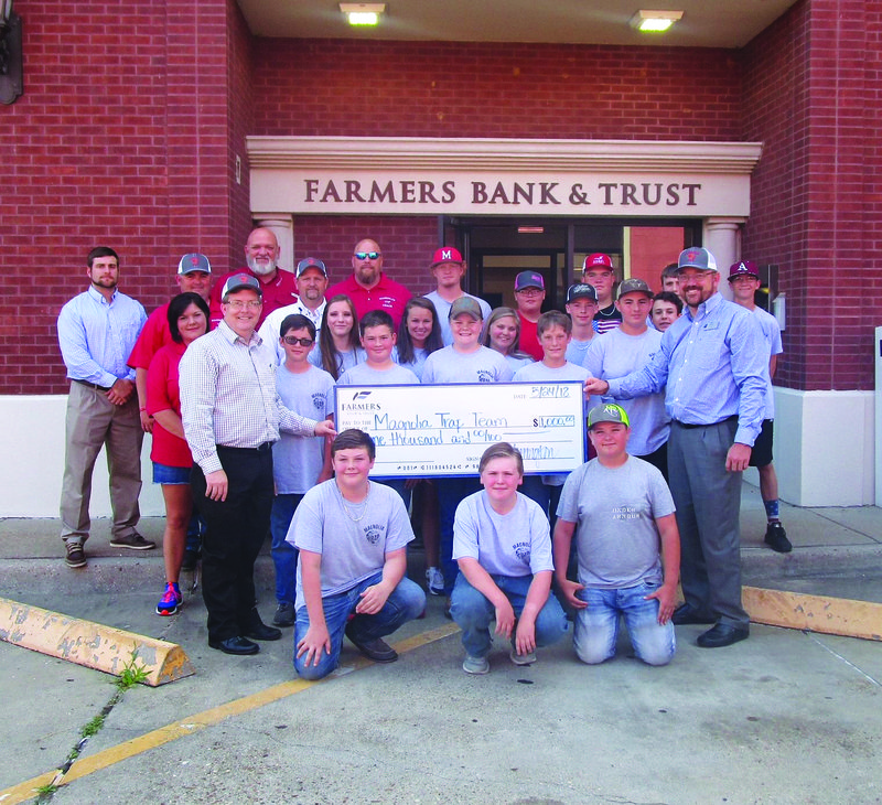 The Magnolia Trap Team is pictured with Farmers Bank officials Monty Harrington (second row, left) and Jason Ray (second row, right) as they present a $1,000 check to the team, on behalf of the local bank.