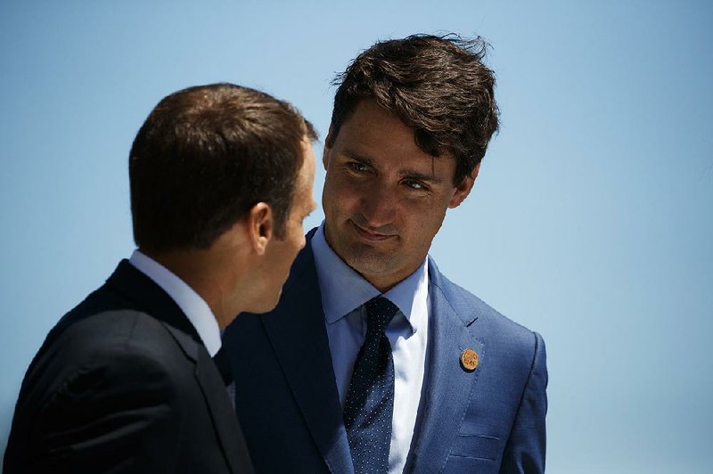 French President Emmanuel Macron (left) and Canadian Prime Minister Justin Trudeau talk Friday at welcoming ceremonies for Group of Seven leaders in Charlevoix, Quebec.