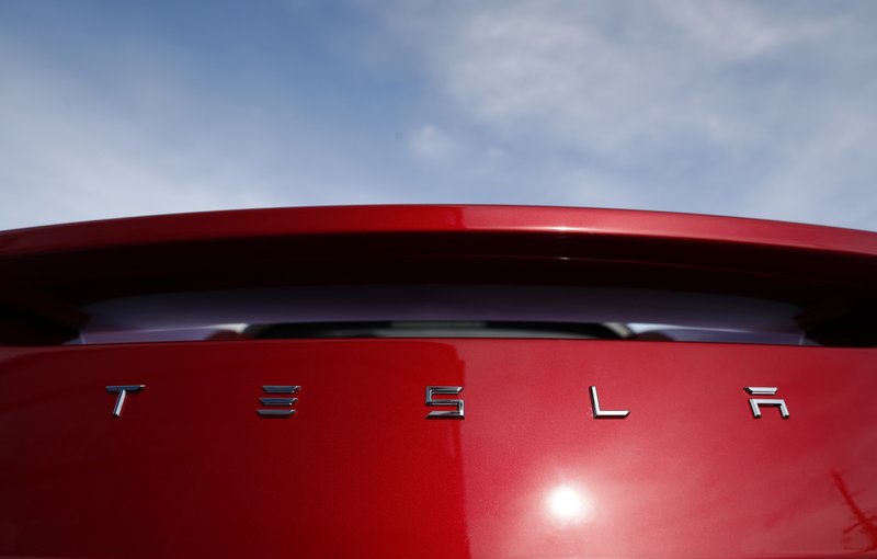 FILE- In this April 15, 2018, file photo the sun shines off the rear deck of a roadster on a Tesla dealer's lot in the south Denver suburb of Littleton, Colo. (AP Photo/David Zalubowski, File)