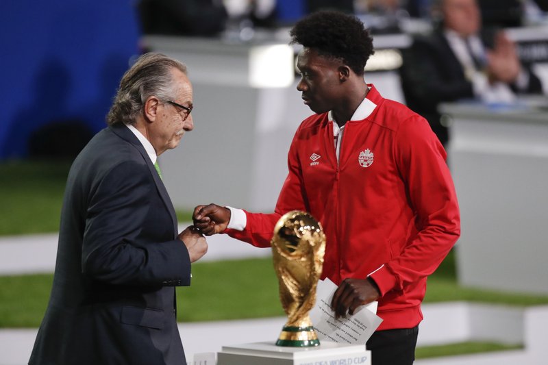 Decio de Maria, President of the Football Association of Mexico, left, and Canadian soccer player Alphonso Davies, right, present a joint United bid by Canada, Mexico and the United States to host the 2026 World Cup at the FIFA congress in Moscow, Russia, Wednesday, June 13, 2018. (AP Photo/Pavel Golovkin)

