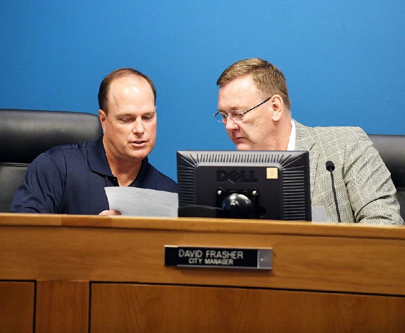 Hot Springs Assistant City Manager Lance Spicer (left) confers with City Manager David Frasher before a board meeting Tuesday night at City Hall. Frasher resigned during the meeting after allegations were aired that he made a racially insensitive remark to a black Hot Springs School District administrator last week. 