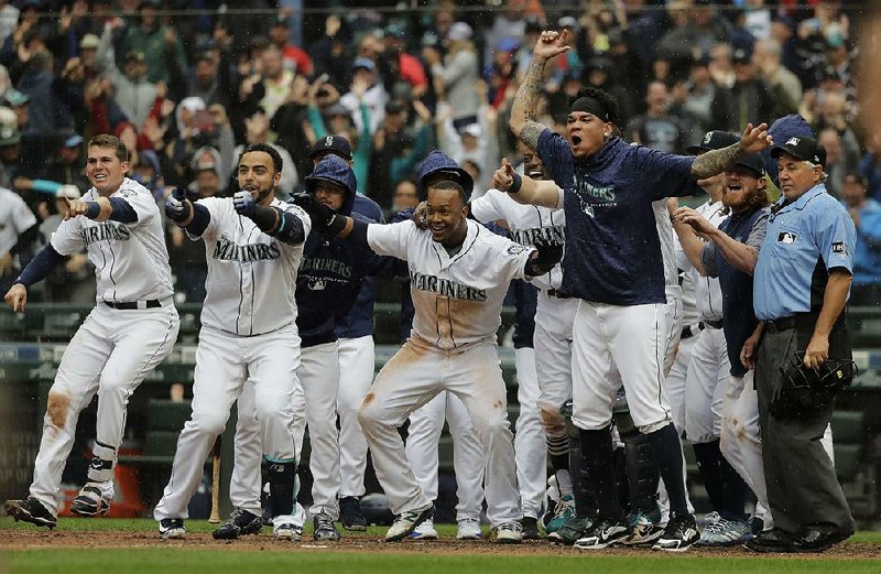 Seattle players wait for Mitch Haniger at home plate after he hit a game-winning, two-run home run in the ninth inning Wednesday in the Mariners’ 8-6 victory over the Los Angeles Angels. 
