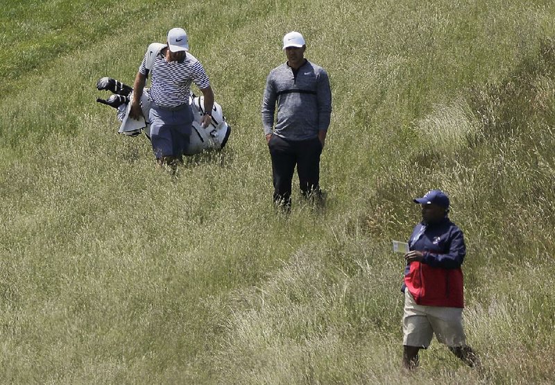 Defending U.S. Open champion Brooks Koepka (center) lines up a shot from the rough along the ninth fairway during a practice round earlier this week at Shinnecock Hills Golf Club, where the U.S. Open begins today. The last time the Open was held at the New York course in 2004, only three players broke par for the weekend. 