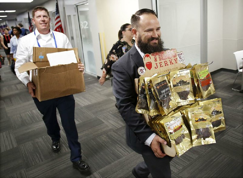 Steven Tibbs (front), owner of Tibbs Jerky, carries a display of his products down Vendor Hall at Walmart’s Made in America open-call event in Bentonville on Wednesday. Behind him is Ben Ebenhoe, Tibbs Jerky’s sales executive and chief financial officer.  
