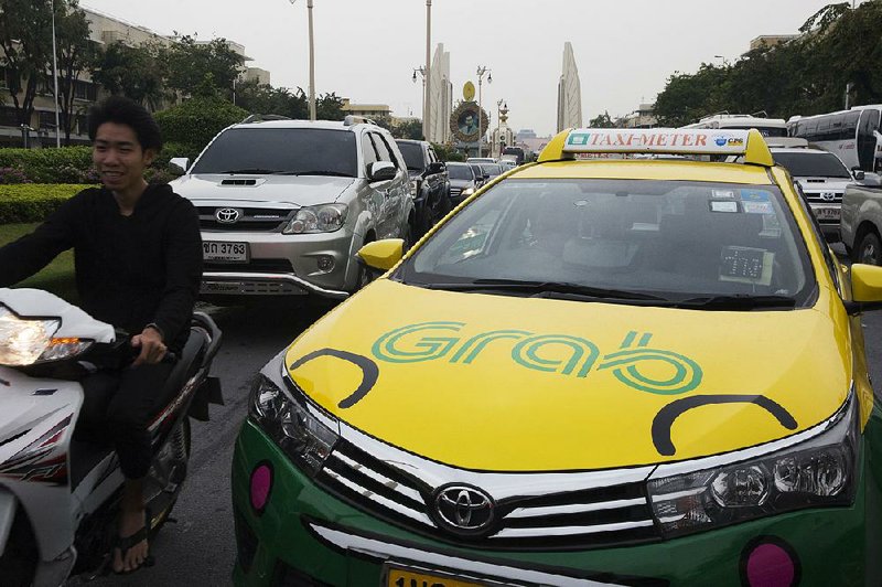 The Grab logo is displayed on a taxi in Bangkok in March. Toyota Motor Corp. is investing $1 billion in Grab, the leading ride-hailing company in Southeast Asia.  