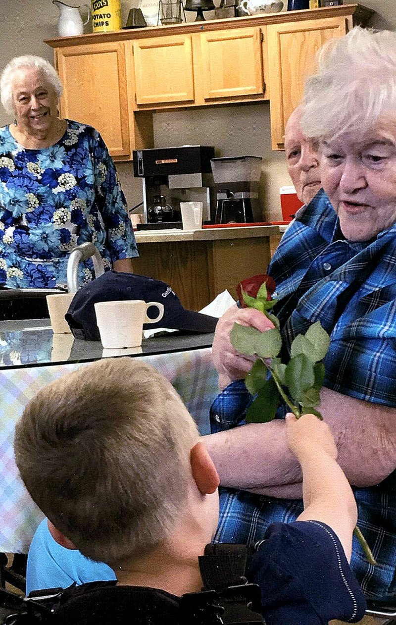 COURTESY PHOTO/Four-year-old Zane Smythia, grandson of Frank and Carolyn Williams, hands out fresh roses to the women at the Noel Senior Center on Mother's Day. The Williams' brought Zane to the center to visit with the ladies and learn about the art of giving.
