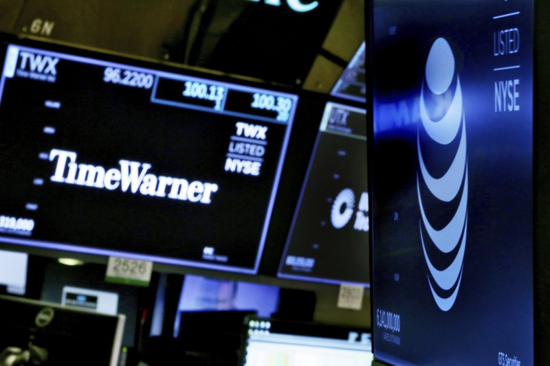 The logos for Time Warner and AT&T appear above alternate trading posts on the floor of the New York Stock Exchange, Wednesday, June 13, 2018.  (AP Photo/Richard Drew)
