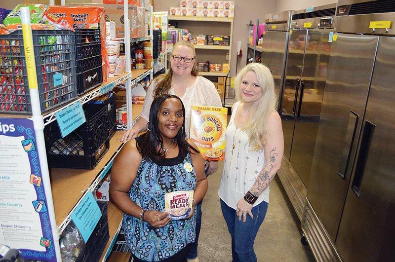 Crystal Certain, right, a Conway High School art teacher, stands with Myracle White, front, food-pantry coordinator for the Community Action Program for Central Arkansas in Conway, and Melissa Allen, community programs director. Certain started a food pantry in her classroom, and CAPCA is operating the pantry for the summer. All students in Faulkner County are welcome to get two weeks’ worth of food from the pantry. More information is available by calling (501) 329-3891 or going to the agency at 707 Robins St., Suite 118.