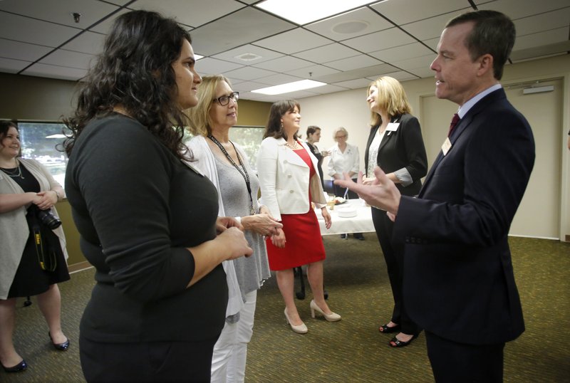 Dr. Cam Patterson (from right), chancellor of the University of Arkansas for Medical Sciences, speaks Friday with Gwen Wiley and Kaitlyn Akel, with the Office of Community Health and Research, as he meets employees at the Northwest campus in Fayetteville. 