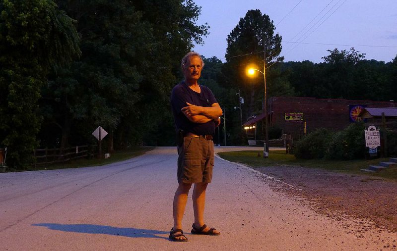 Gilbert Mayor Mitch Mortvedt stands in front of a town streetlight as the high-pressure sodium lamp flickers on. Bruce McMath, chairman of the Arkansas chapter of the International Dark Sky Association, calls them “barnyard lights.”  