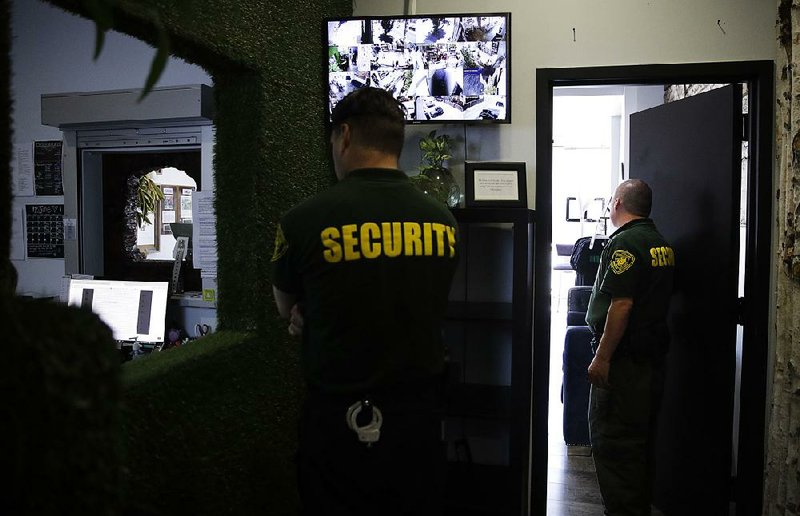 In this photo taken in June 2017, two security guards stand watch at a medical marijuana dispensary in Los Angeles, a business conducted mostly in cash.  