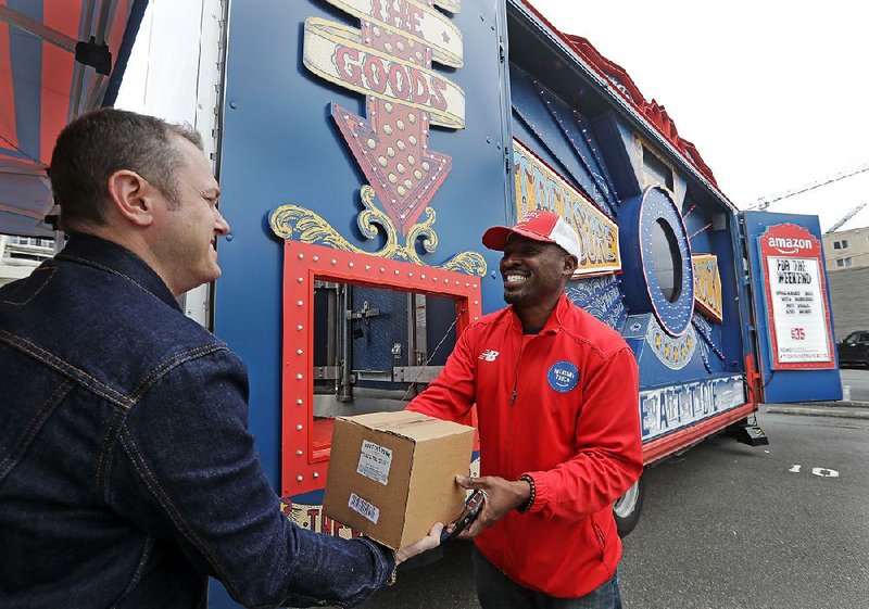 Amazon worker Khayyam Kain (right) hands a package to a customer at a Treasure Truck stop in Seattle.  