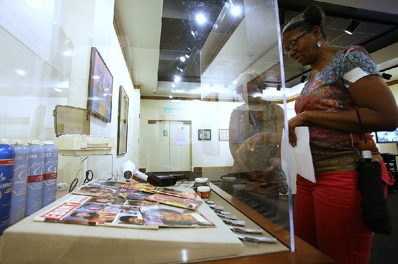 Amanda Nelson (right) and Karen Biekman look at a display Saturday in the “Don’t Touch My Crown” exhibit at the Mosaic Templars Cultural Center in Little Rock. The exhibit runs through August.  