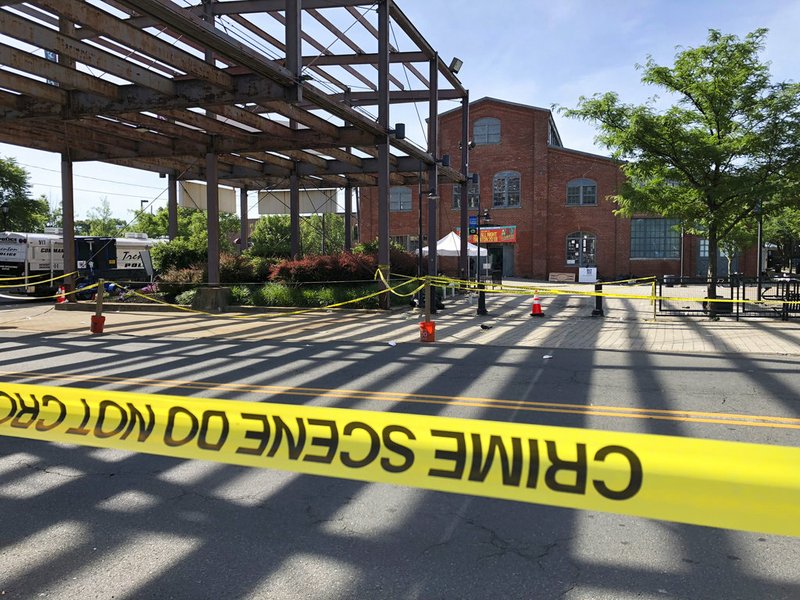 Police crime-scene tape keeps people away from the brick Roebling Wire Works building, background, in Trenton, N.J., hours after a shooting broke out there at an all-night art festival early Sunday, June 17, 2018, sending people stampeding from the scene and leaving one suspect dead and at least 20 people injured.