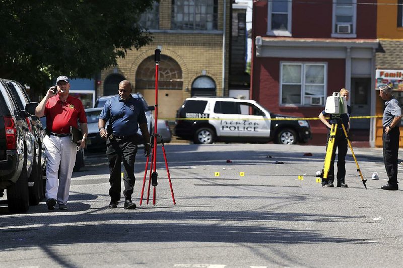 Mercer County Prosecutor Angelo Onofri (left) walks past investigators outside the warehouse building that was the scene of a shooting that left more than a dozen injured and at least one dead Sunday in Trenton, N.J. 